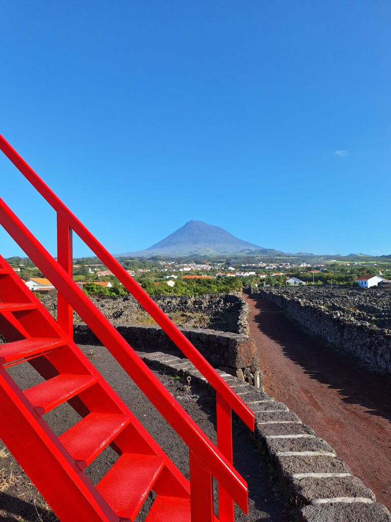 A striking red staircase overlooking Pico Island’s vineyards, with Mount Pico standing majestically in the background.