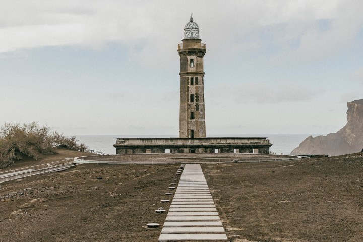 Lighthouse on a coastal landscape with a stone pathway leading to it.