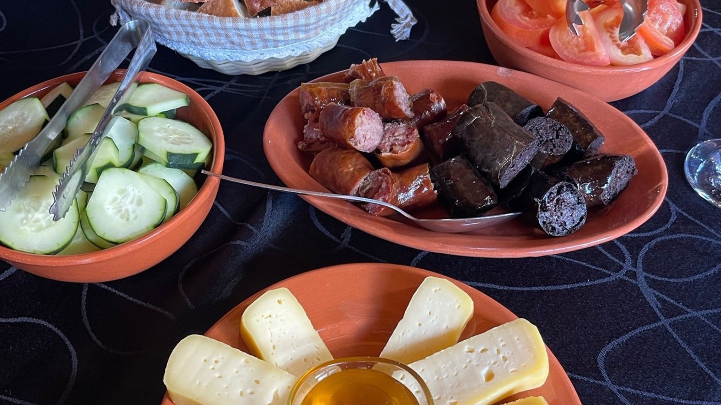 Assorted meats, cheese, and vegetables on a table with bread slices.