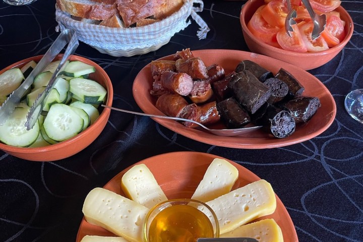 Assorted meats, cheese, and vegetables on a table with bread slices.