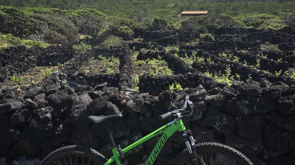 Green bike by stone wall with distant mountain under cloudy sky.
