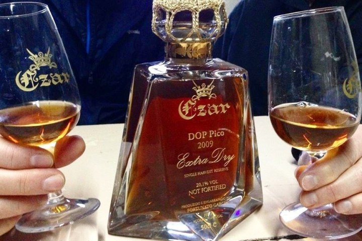 Two hands holding glasses of Czar Extra Dry wine with a bottle in the center.
