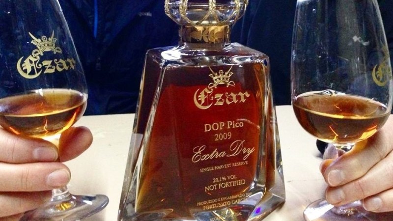 Two hands holding glasses of Czar Extra Dry wine with a bottle in the center.
