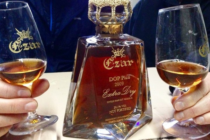 Two hands hold glasses of amber liquid next to a decorative bottle labeled 'Czar Extra Dry 2009.'