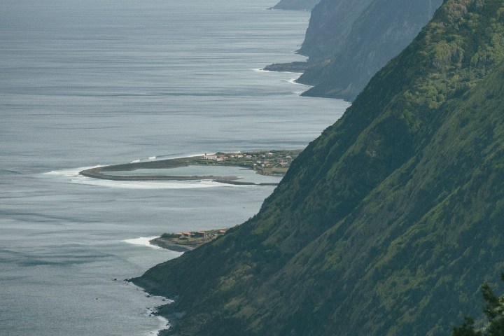 Coastal cliffs and a small village near the ocean, with rugged terrain and waves.